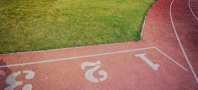 A bird's-eye view of a vibrant outdoor running track and lush green sports field.