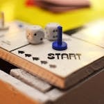 Close-up of a board game start position featuring dice and a blue game piece, perfect for leisure themes.