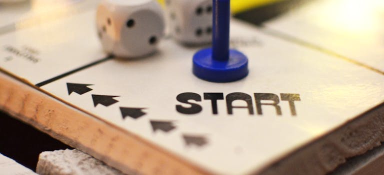 Close-up of a board game start position featuring dice and a blue game piece, perfect for leisure themes.