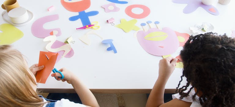 Two children enjoying an art class with colorful paper cutouts, fostering creativity and fun.