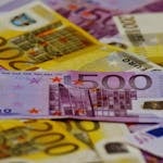 A close-up image of several Euro banknotes arranged in a scattered manner.