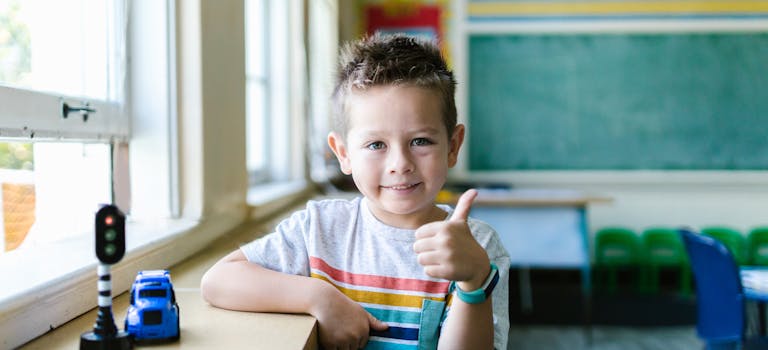 Smiling child in a classroom giving a thumbs up, symbolizing confidence and joy.