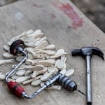 A pile of wooden pieces with a vintage hand drill and hammer on a weathered workbench, highlighting craftsmanship.