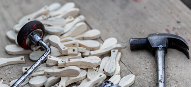 A pile of wooden pieces with a vintage hand drill and hammer on a weathered workbench, highlighting craftsmanship.