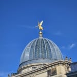 A striking view of the Dresden Academy of Fine Arts dome with a golden sculpture against a blue sky.