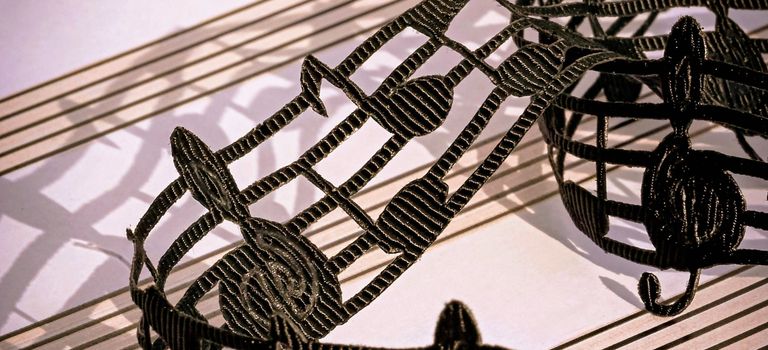 Artistic black lace musical notes elegantly arranged on sheet music, creating a captivating visual.