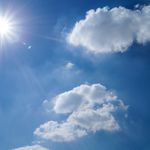 Vibrant blue sky with fluffy clouds and bright sun. Perfect cloudscape background.