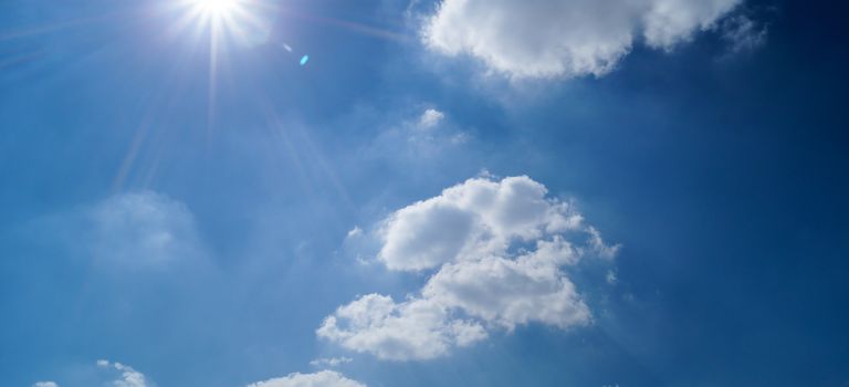 Vibrant blue sky with fluffy clouds and bright sun. Perfect cloudscape background.